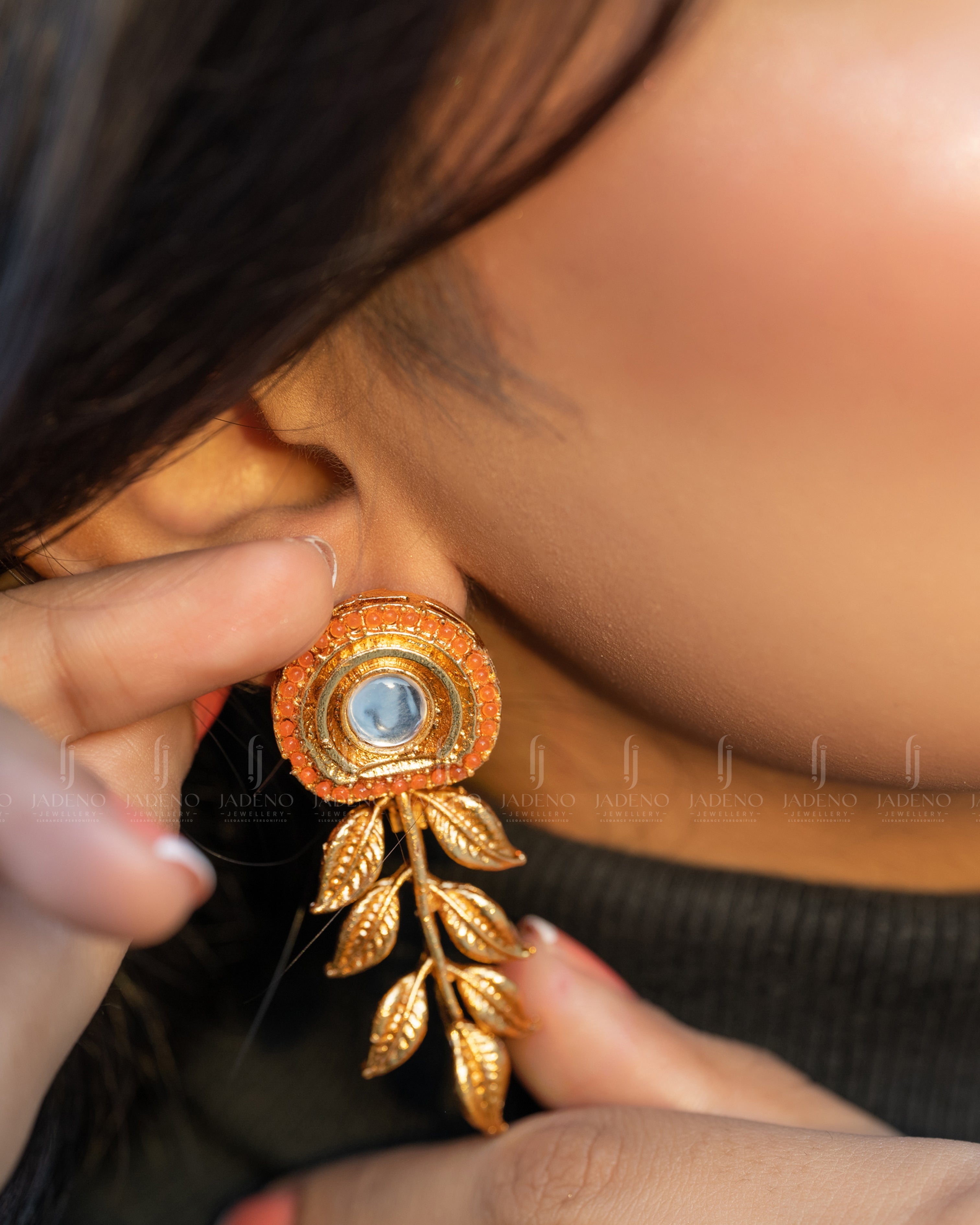 "Model wearing orange Resplendent Egyptian Leaf Earring Studs with golden leaves and a central stone. Perfect for formal and festive occasions. Available at JADENO"