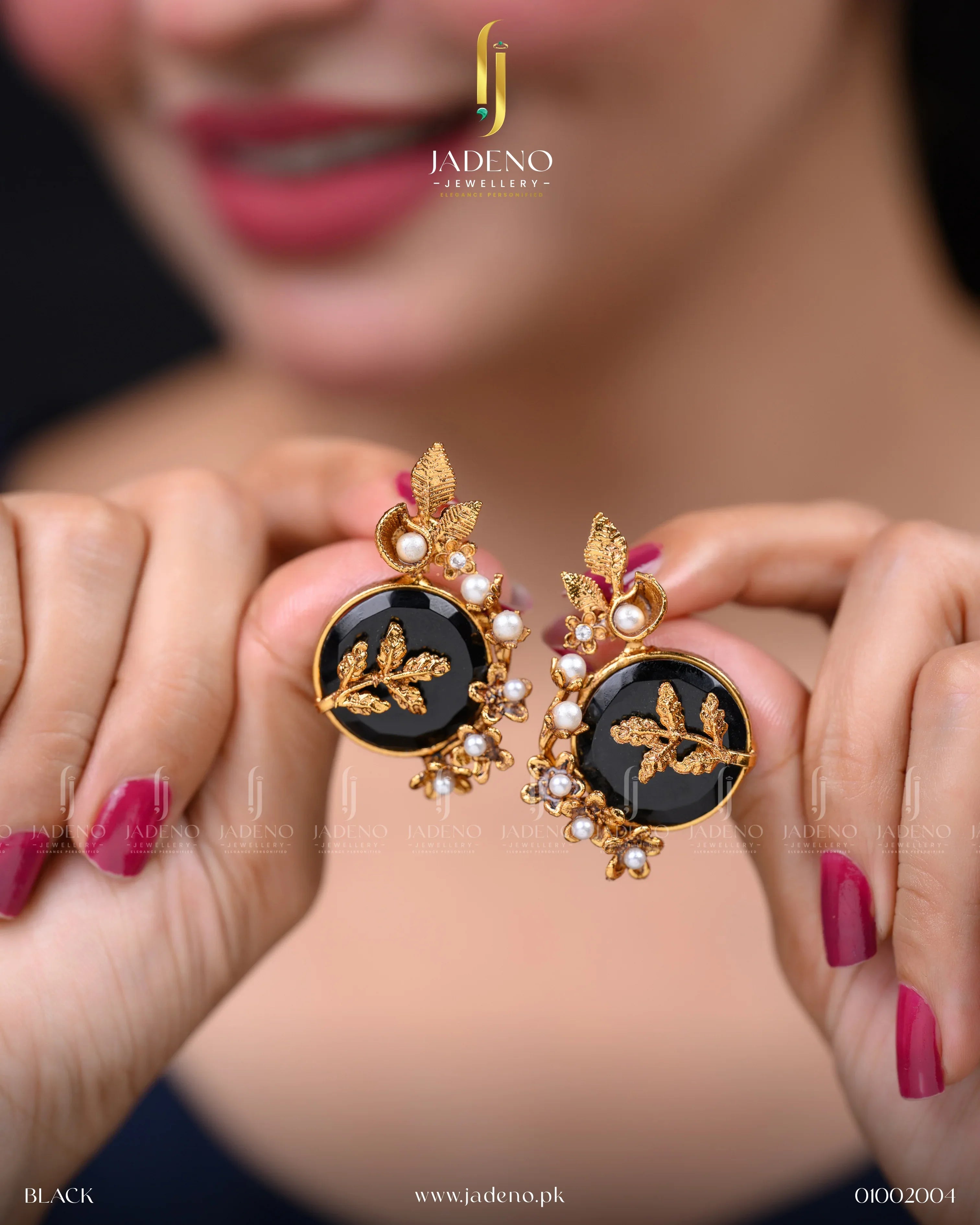 "Pair of artificial gold earrings with black stone and pearls held in hands"