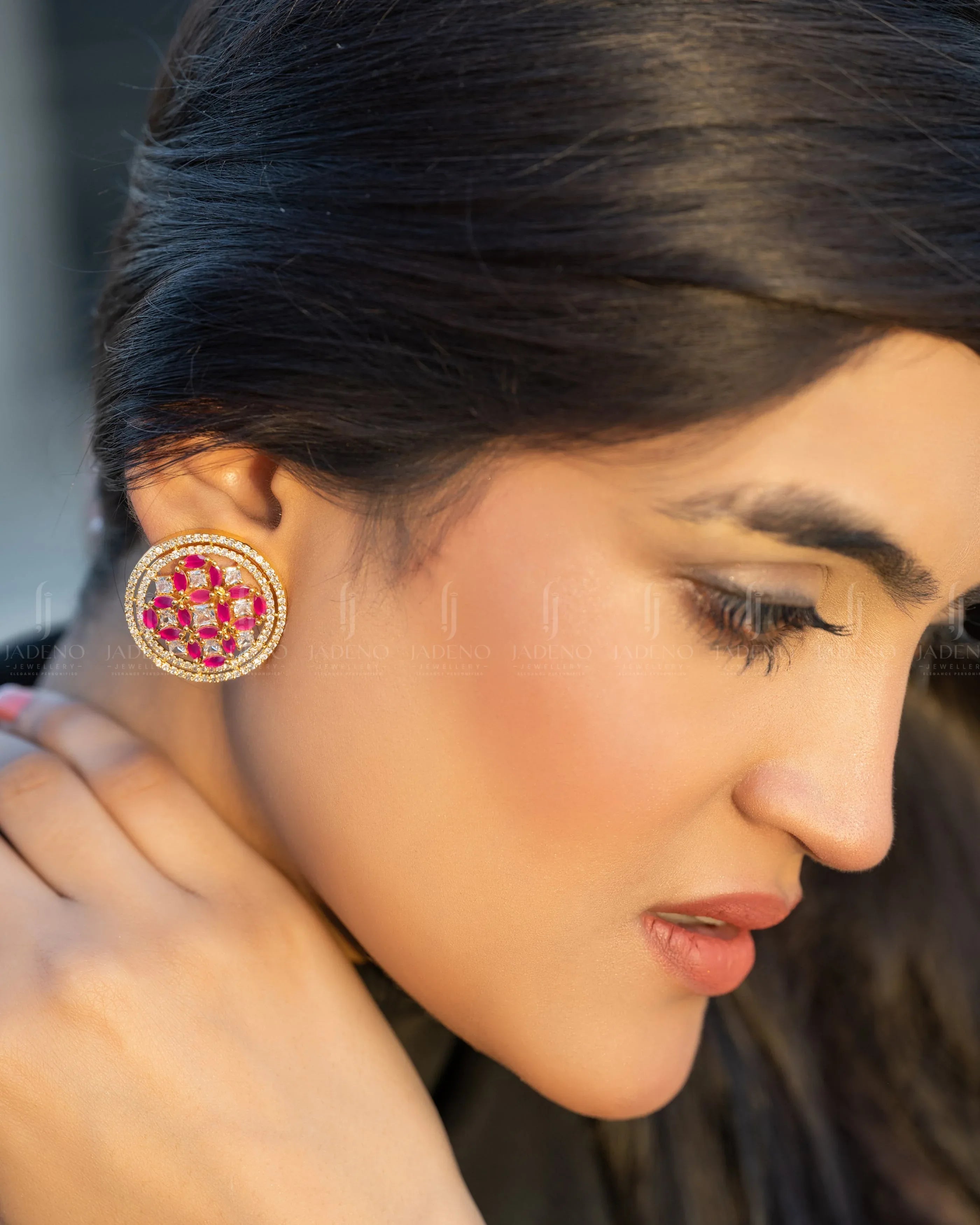 "Model wearing elegant pink and gold circular stud earrings with intricate gemstone detailing. Perfect for festive or formal occasions. Available at JADENO."