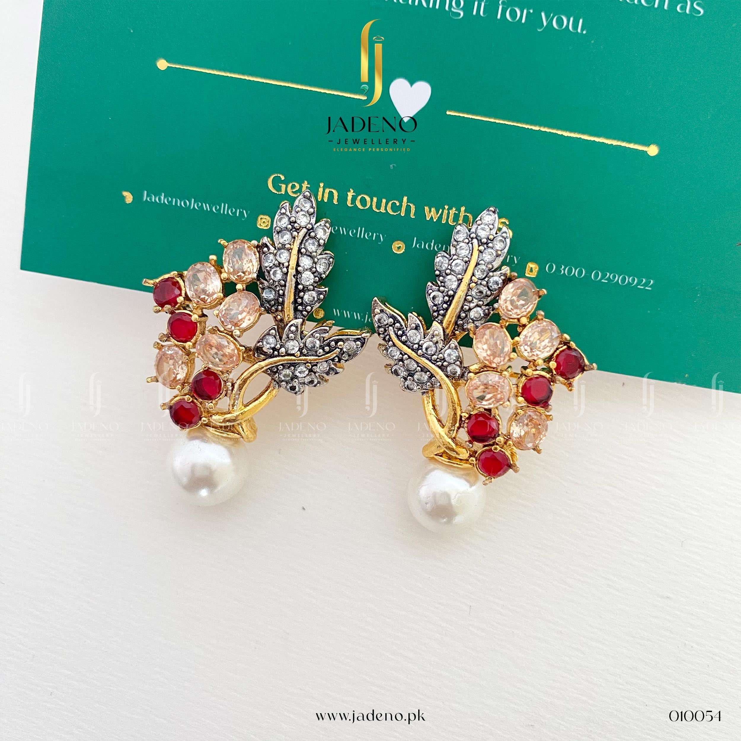 "Flat lay of glittery zircon stud earrings featuring red stones and pearls"