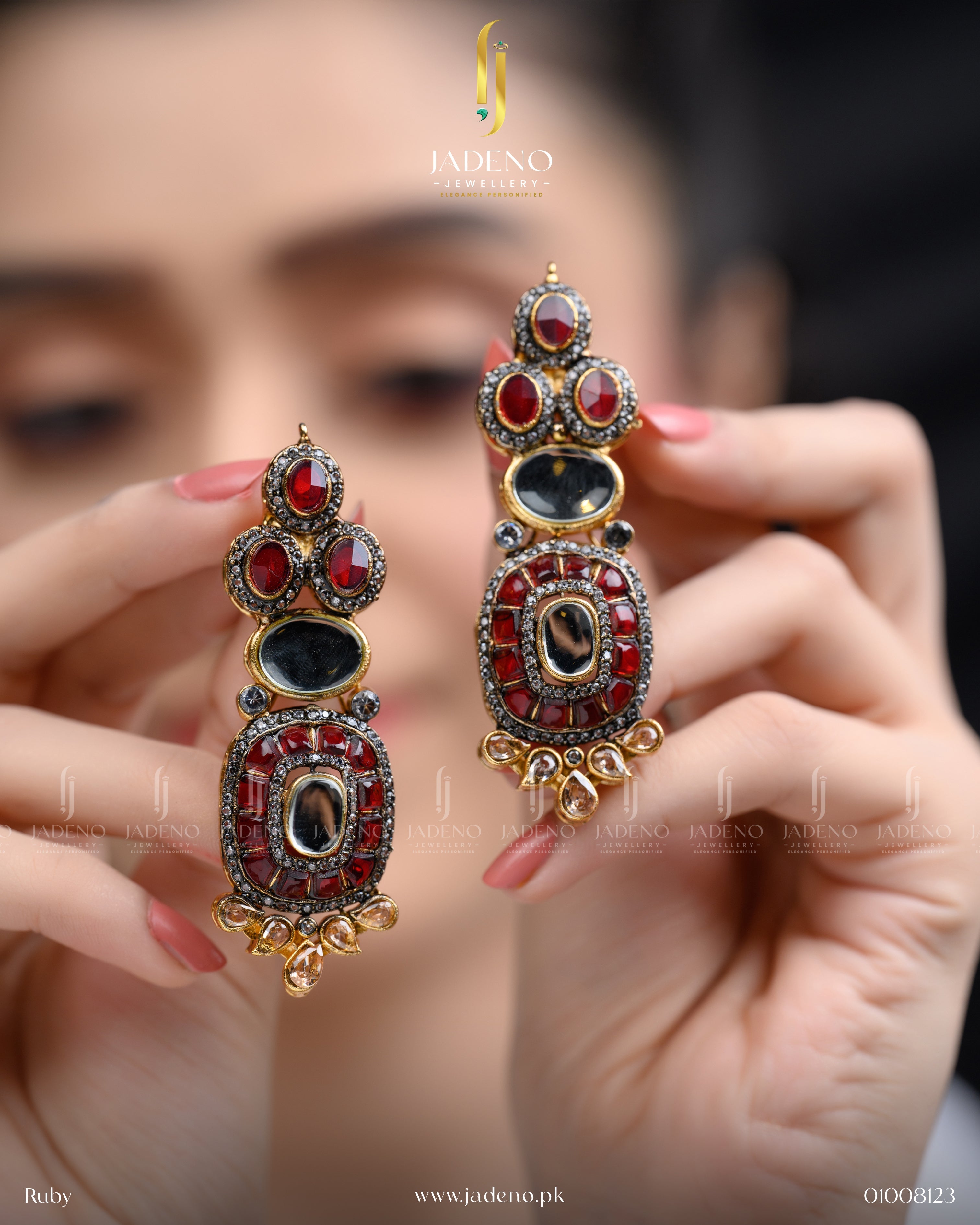 "Hands holding red stone cut earrings with ornate gold detailing"
