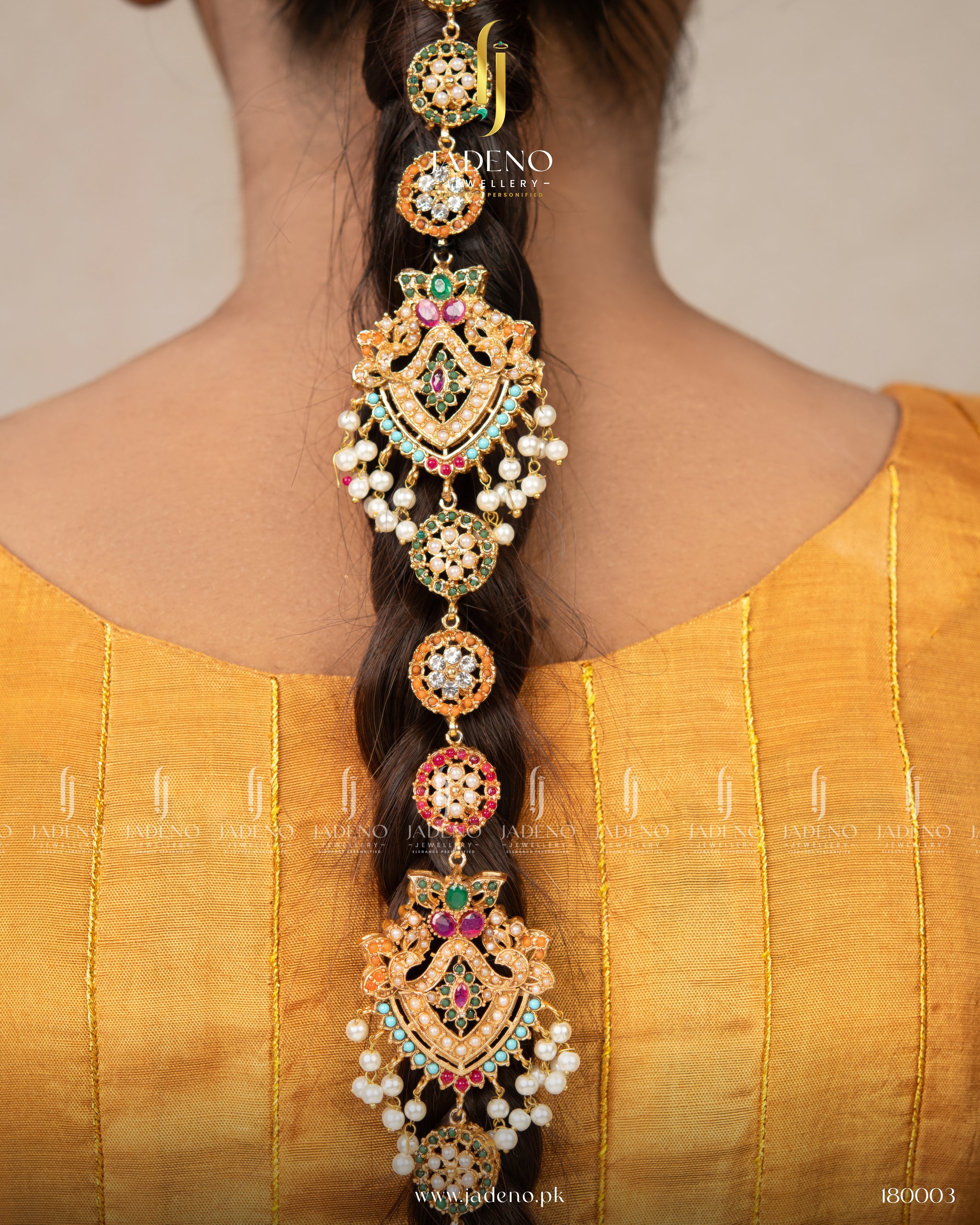 "Handmade nauratan paranda with green, pink, and gold stones styled on braid"