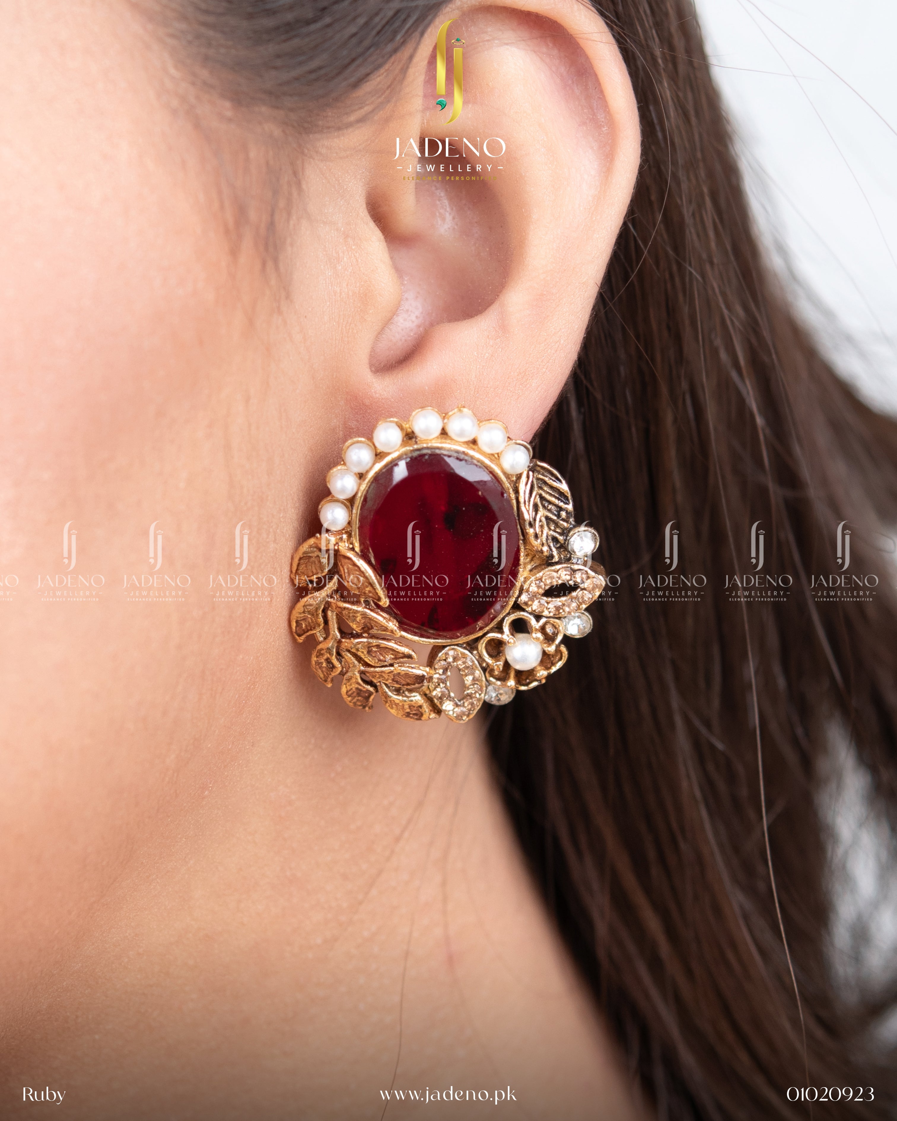 "Close-up of a woman wearing red leaf cut earrings with pearl border"