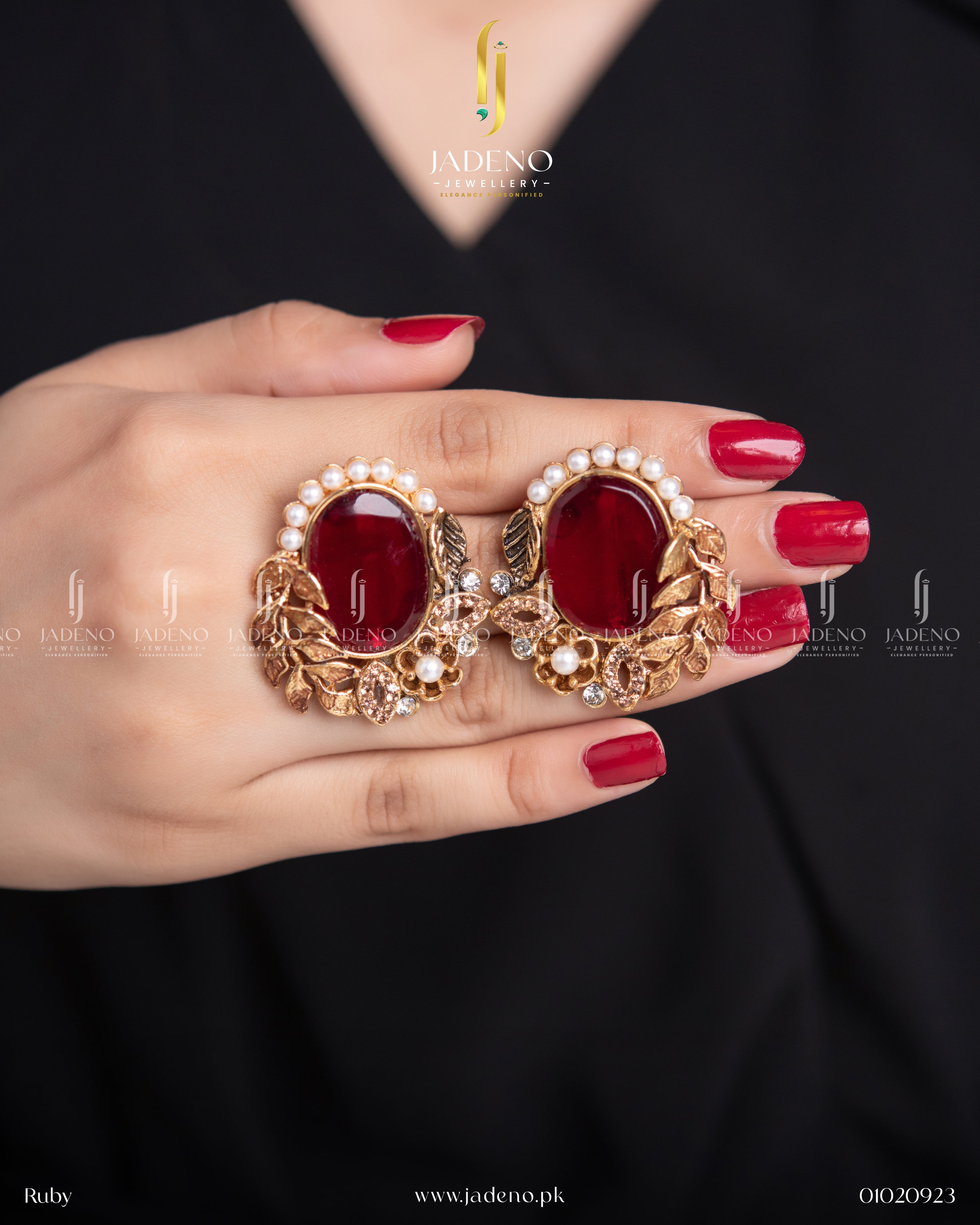 "Hands holding red leaf cut earrings with pearl border and gold leaf design"