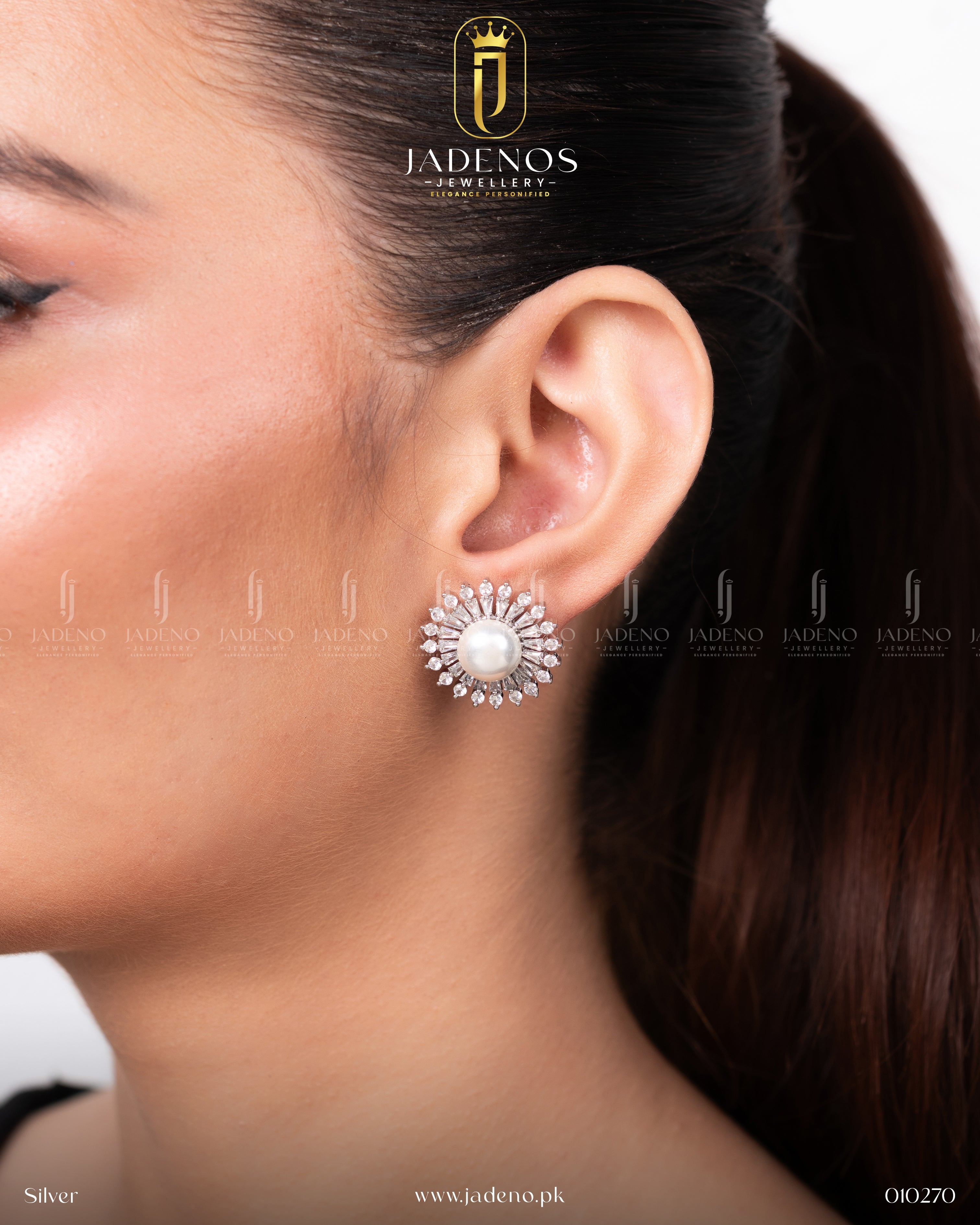 A close-up of The Bloomy Studs in silver, showcasing a central pearl surrounded by clear crystal stones in a starburst pattern, worn on a model's ear.